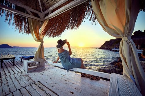 Woman,In,Hat,Relaxing,By,The,Sea,In,A,Luxurious shutterstock 1362142046 scaled 500x0 c default